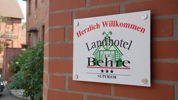 A sign on a brick wall welcoming guests to Landhotel Behr.