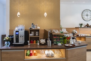 A modern coffee station with a coffee machine, tea pots, and a variety of cups and mugs. - Landhotel Behre (Lehrte)