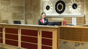Ein Empfangsschalter mit einer Uhr, die Moskauer Zeit anzeigt, einem Namensschild und einem Schild, das den Check-in-Bereich kennzeichnet.