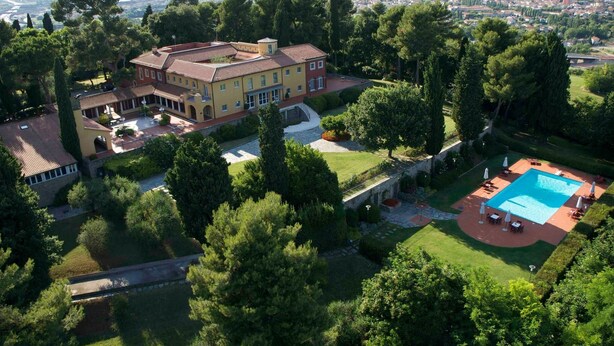 Une grande maison à plusieurs étages, dotée d’une cour spacieuse, d’une piscine et offrant une vue sur le paysage environnant.