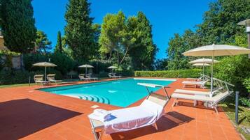 Una piscina al aire libre de temporada, sombrillas