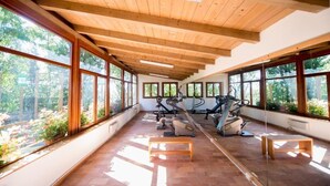 Une salle de sport équipée de matériel d’exercice, dotée de grandes fenêtres et de poutres en bois au plafond.