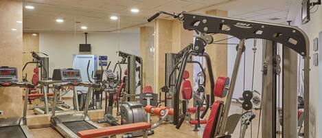 A gym with treadmills, weight machines, and a mirror wall.