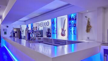 A modern bar area with a neon 'HELLO' sign, a saxophone, and various bottles.