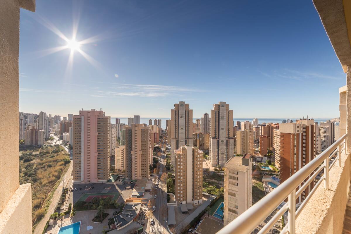 Un immeuble de grande hauteur, doté de nombreux étages, sous un ciel dégagé, avec une vue lointaine sur une étendue d’eau.