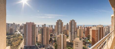 Un edificio de gran altura con varios pisos, cielo despejado y una vista distante de una masa de agua.