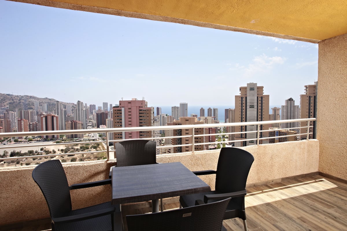 Un balcon avec vue sur la ville, aménagé avec deux chaises et une table.