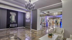 Un moderno vestíbulo de hotel con una araña, una recepción y un área de descanso.