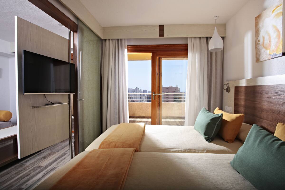 Une chambre d’hôtel avec un lit, une télévision, un bureau et une vue sur la ville par la fenêtre.