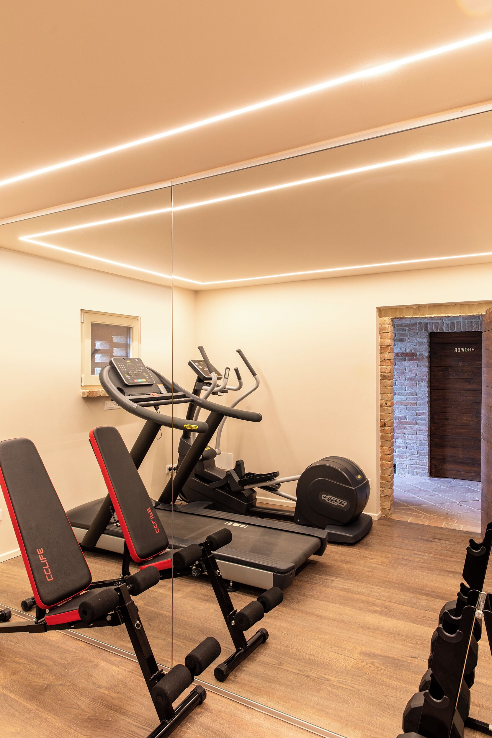 A home gym with exercise equipment, a window, and a brick wall.