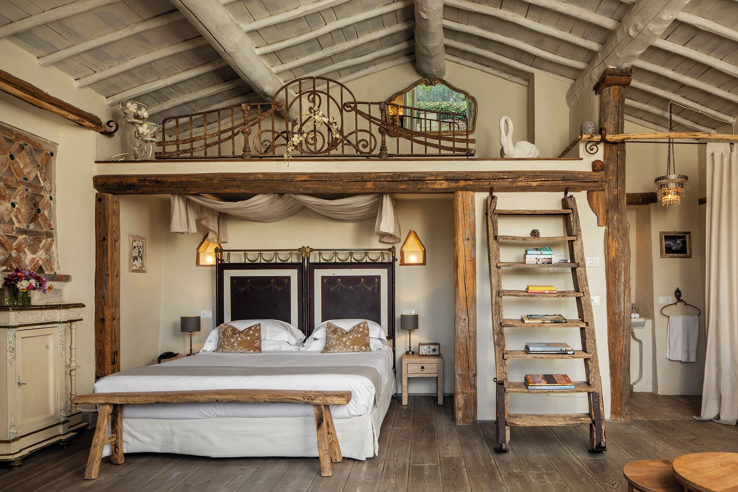 A rustic bedroom with a loft bed, wooden ladder, and a decorative metal railing.