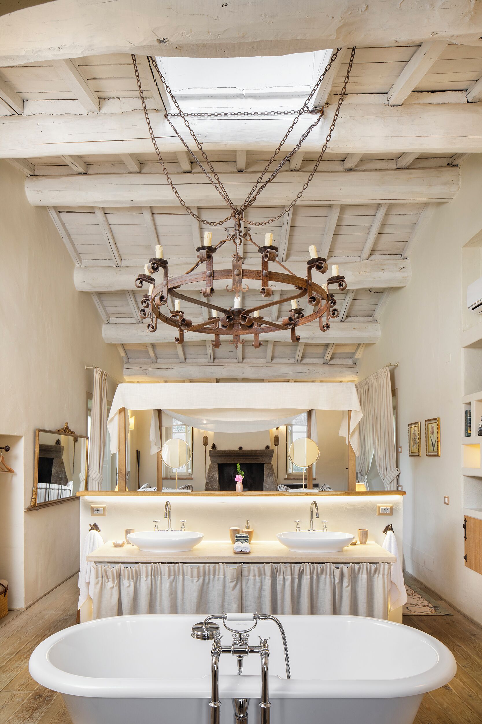 A spacious bathroom with a freestanding bathtub, a large mirror, and a chandelier.