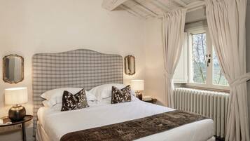 A hotel room with a large bed, two bedside tables with lamps, a mirror, and a window with curtains.