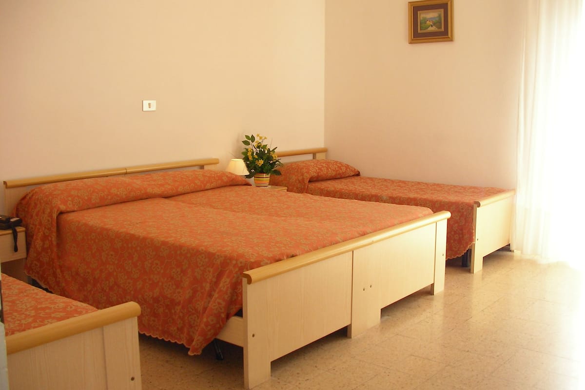 Una habitación con dos camas de madera, una mesita de noche con lámpara y una pequeña planta en maceta.