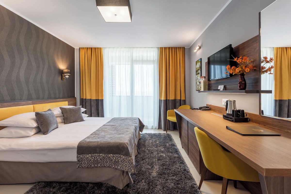 Ein modernes Hotelzimmer mit Bett, Schreibtisch und Fernseher.