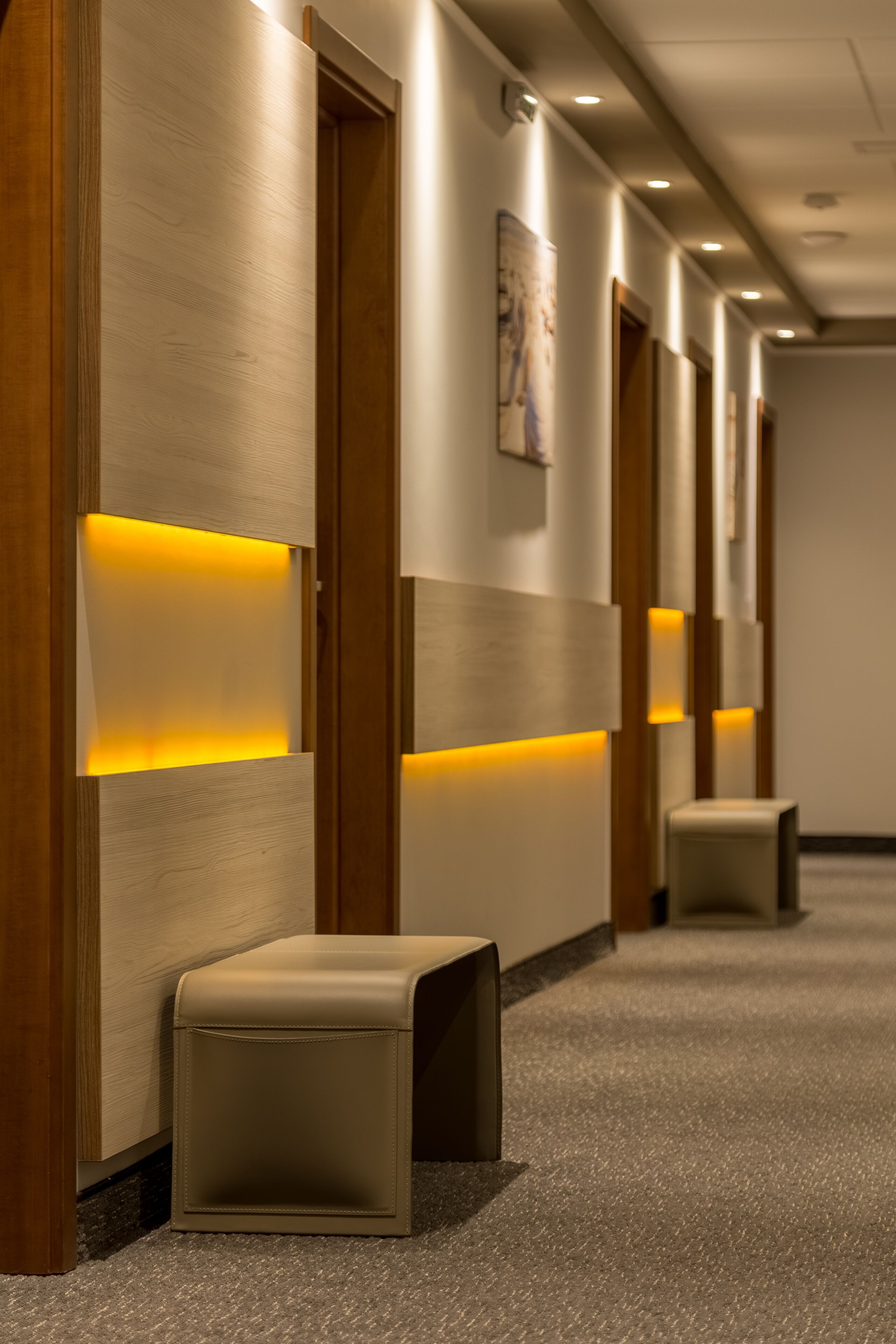 A hallway with wooden paneling, recessed lighting, and a carpeted floor.