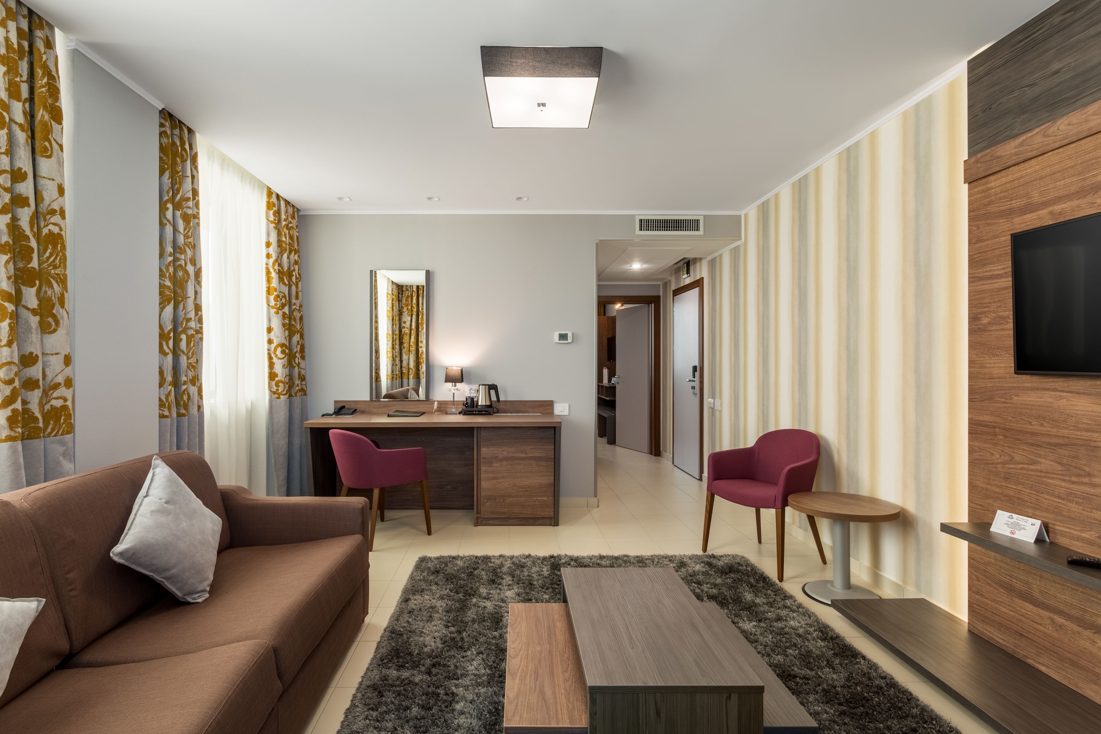Ein modernes Wohnzimmer mit einer Couch, einem Couchtisch und einem an der Wand befestigten Fernseher.