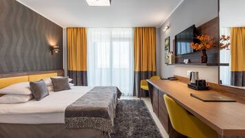 Quarto de hotel moderno com cama, escrivaninha e televisão.