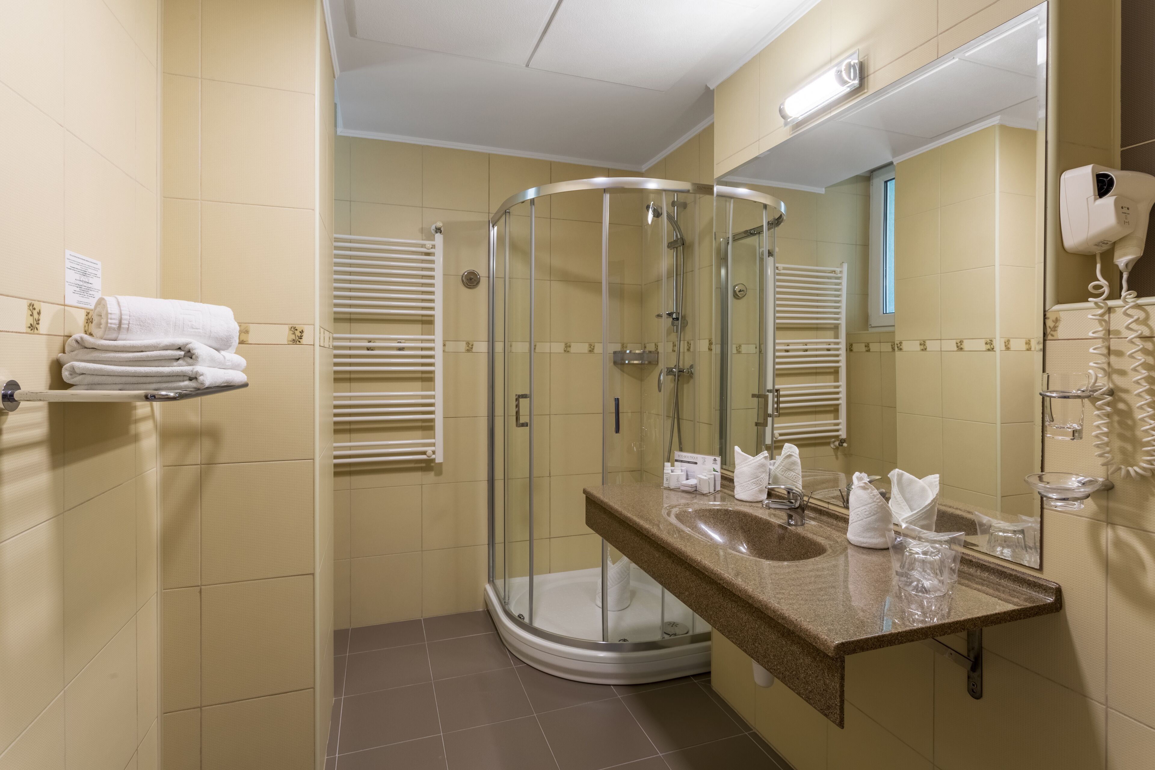 Een badkamer met een douche met glazen wand, een wastafel met spiegel en een handdoekrek.