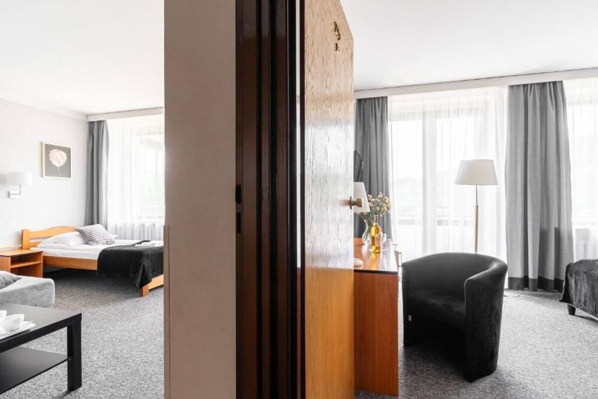 Una habitación de hotel con una cama, un escritorio con lámpara, una silla y un sofá.