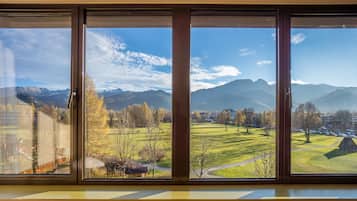 Ein großes Fenster mit Blick auf einen Park, Berge und eine ferne Stadt.