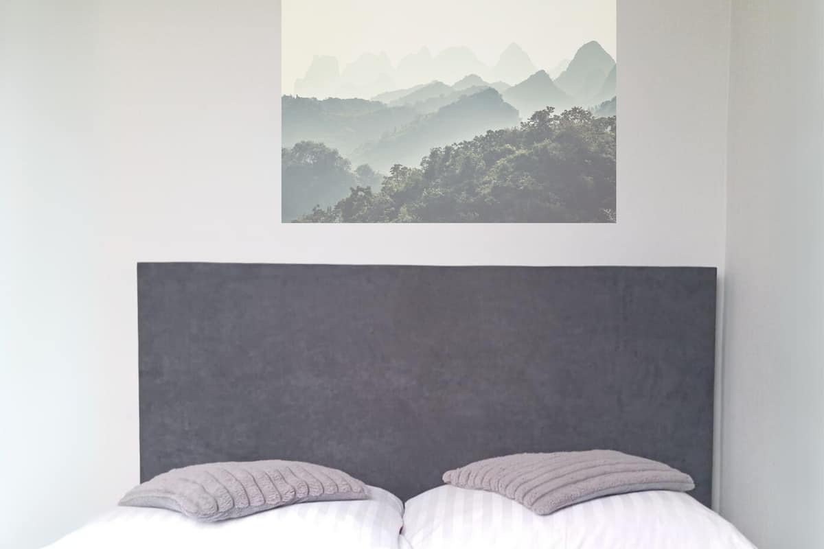 Un dormitorio con cama, almohadas y un cuadro en la pared.