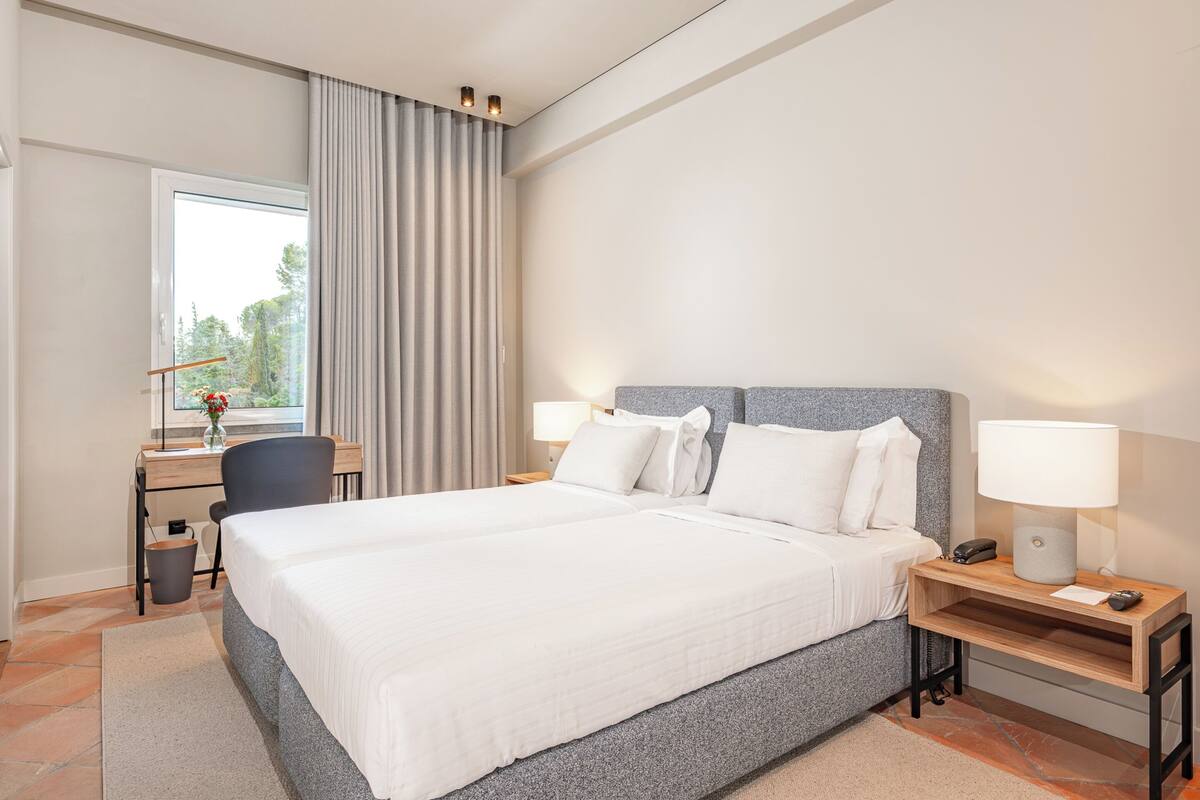 Una habitación de hotel moderna con una cama grande, mesitas de noche, un escritorio y una silla.