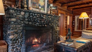 A stone fireplace with a fire, surrounded by rustic decor and a cozy seating area. - Weasku Inn (Grants Pass)