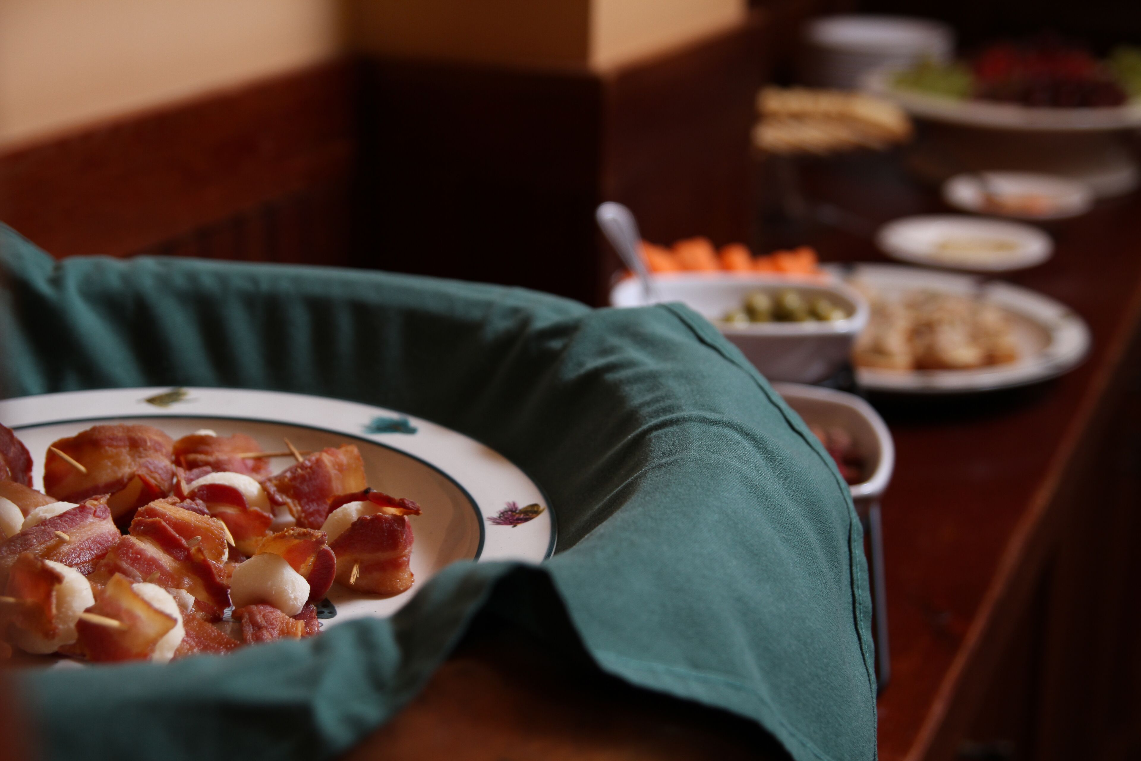 A dining table with a plate of bacon-wrapped meatballs and various side dishes.