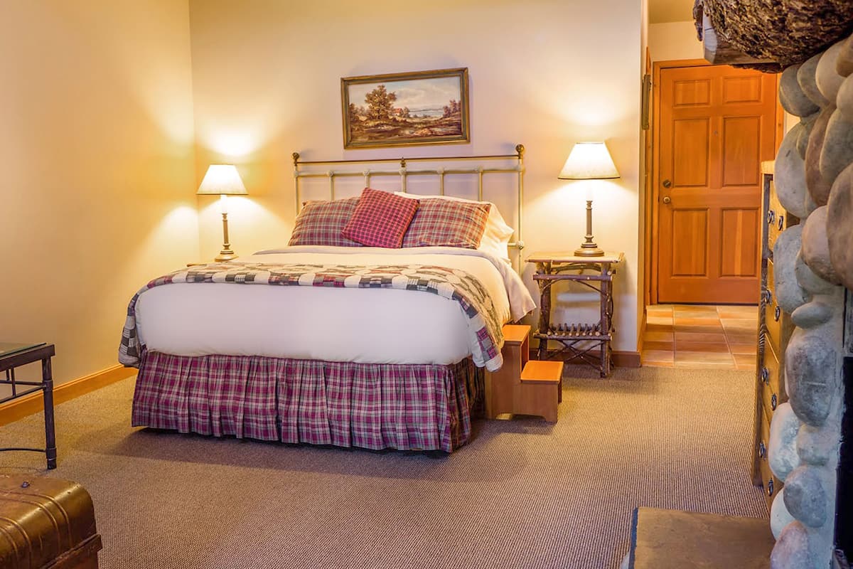 A neatly arranged bedroom with a bed, two bedside tables, a chair, and a door.