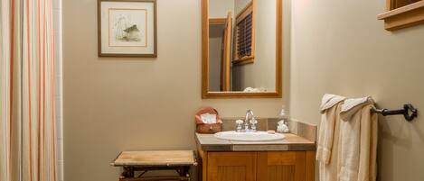 A bathroom with a wooden vanity, a mirror, a framed picture, and a towel rack.
