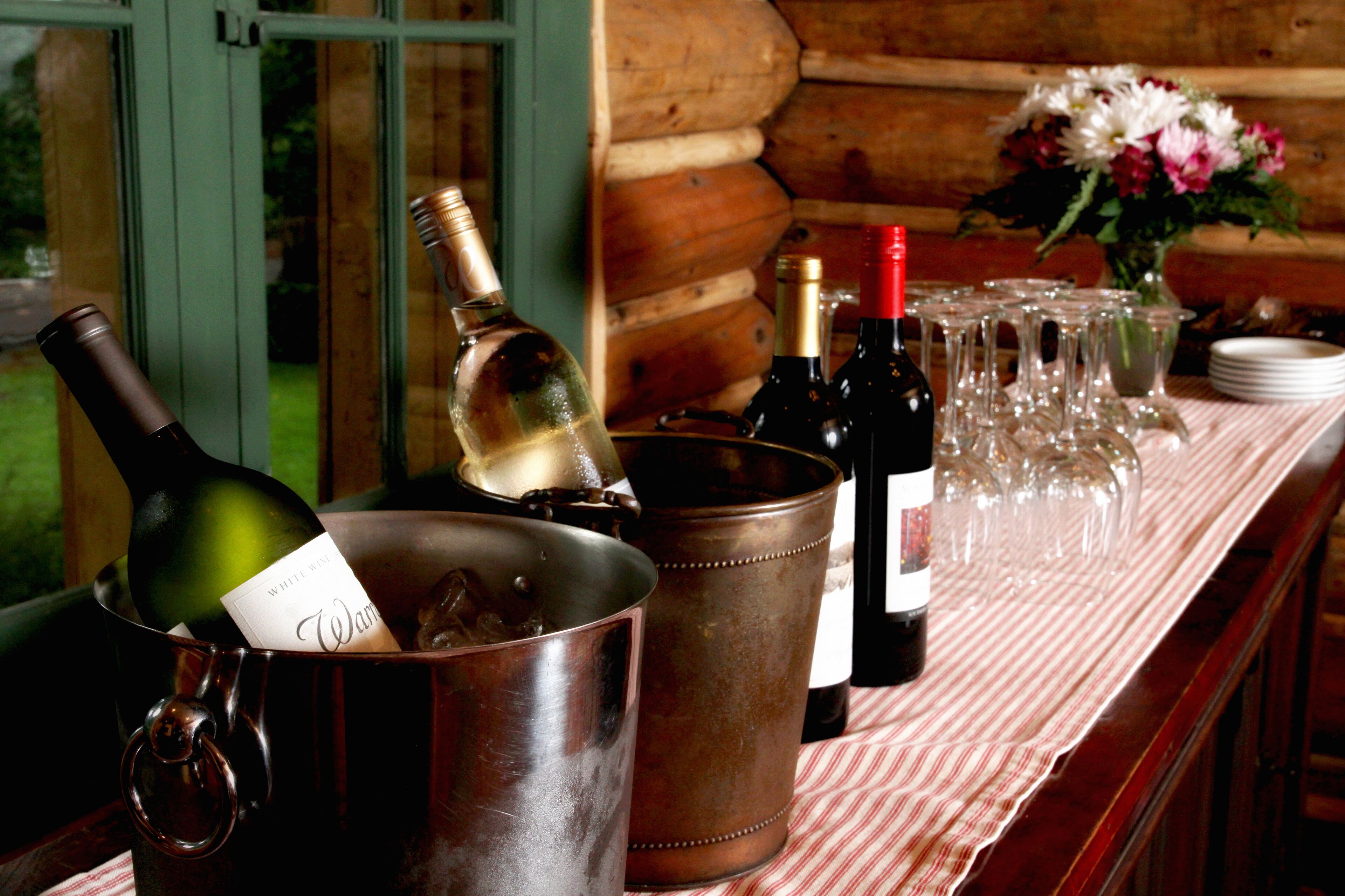 A table with a bottle of white wine, a metal bucket, and a bottle of red wine.