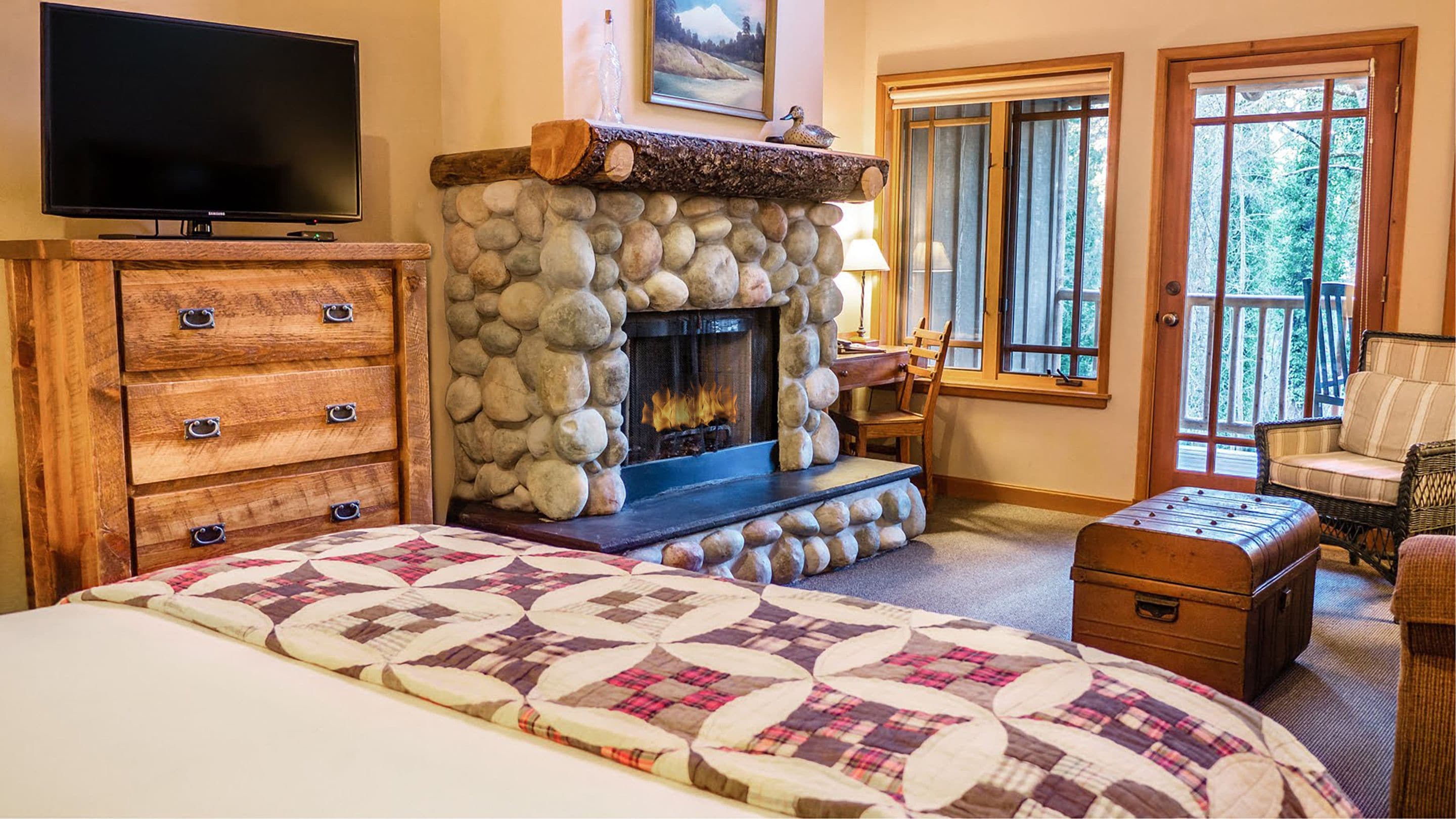 Una habitación acogedora con chimenea de piedra, televisor, cama cómoda y vistas al exterior.