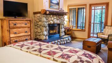 Una habitación acogedora con chimenea de piedra, televisor, cama cómoda y vistas al exterior.