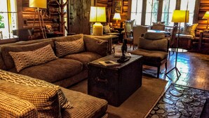 A cozy log cabin interior with a large sofa, armchairs, and a coffee table. - Weasku Inn (Grants Pass)
