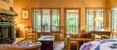 Una habitación acogedora con chimenea, muebles de madera y grandes ventanas con vistas a la vegetación.