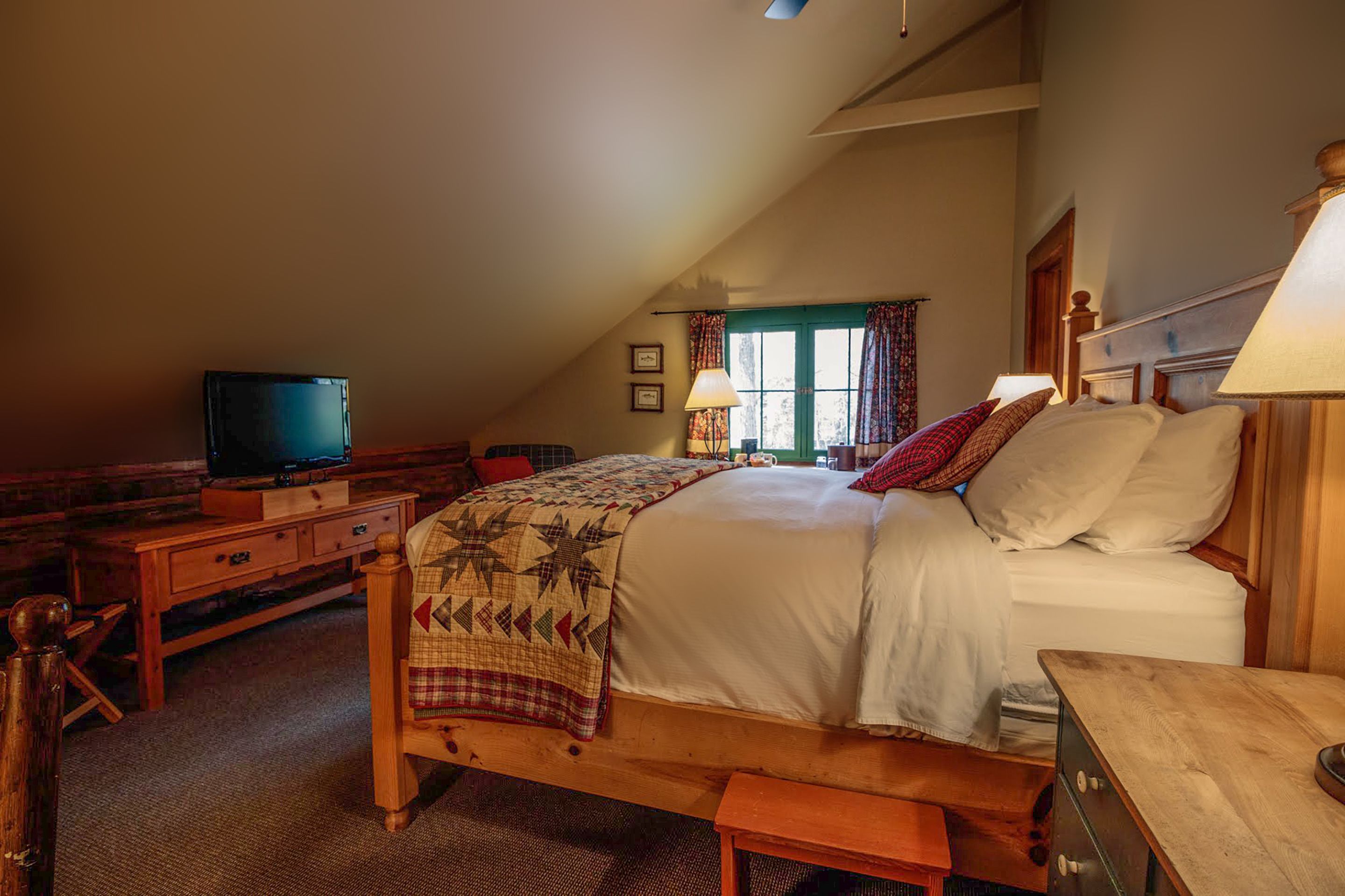 Une chambre confortable avec un lit, une télévision, un bureau et une fenêtre avec des rideaux.