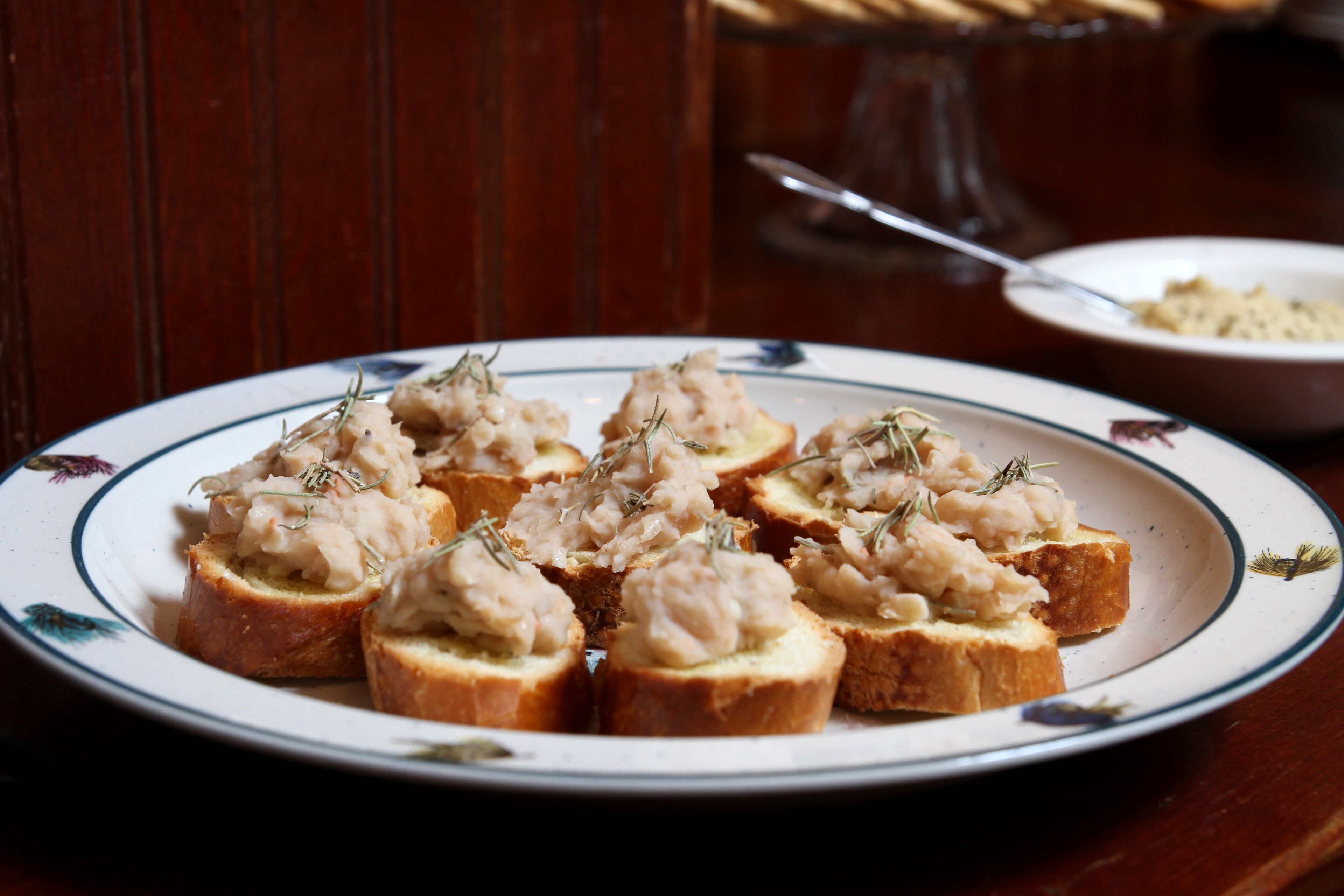 A plate of food with bread and a creamy topping, possibly a seafood dish, garnished with herbs.