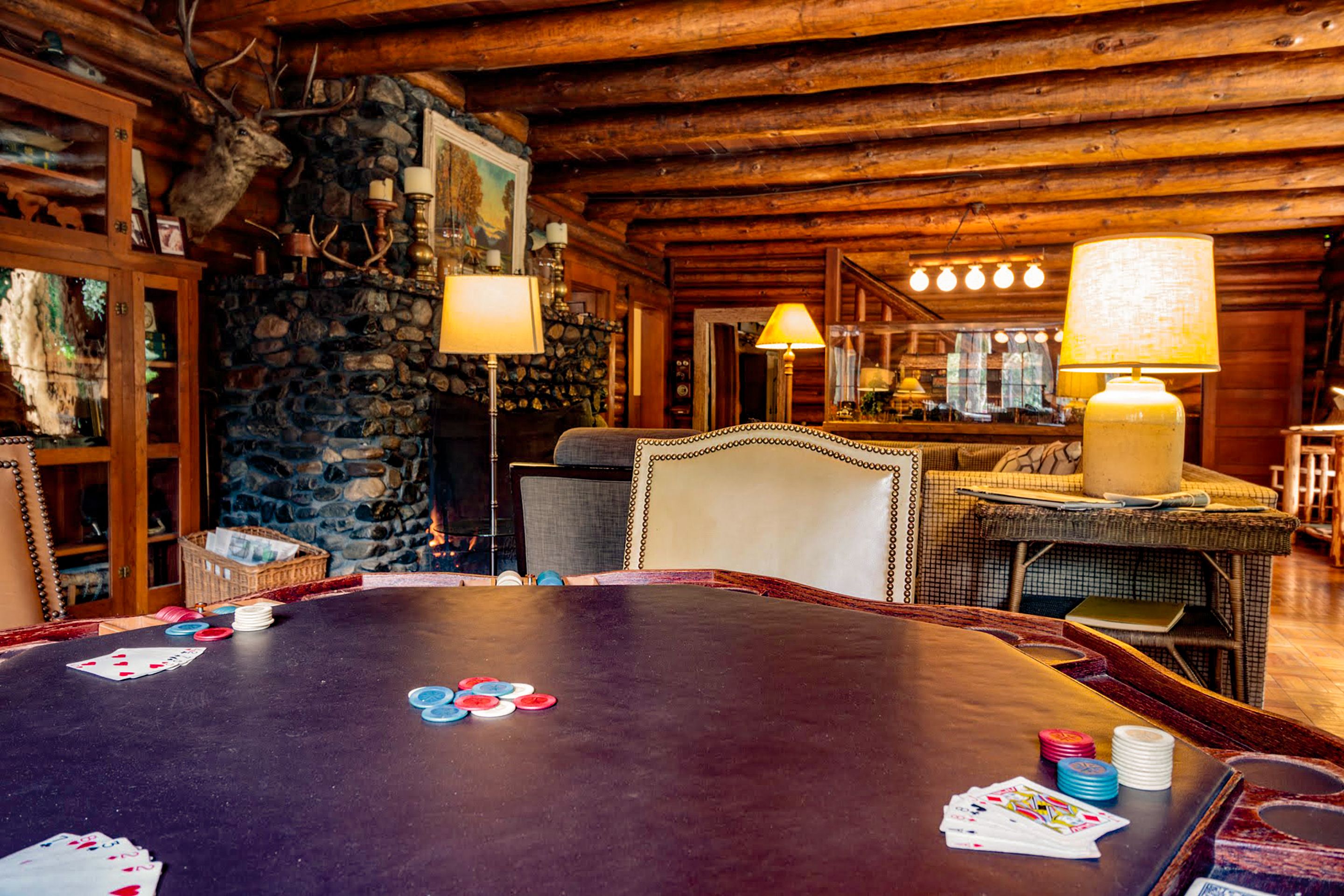 A wooden interior with a poker table, stone wall, and rustic decor.