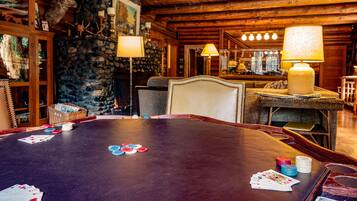 A wooden interior with a poker table, stone wall, and rustic decor.