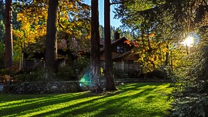 A lodge with a stone wall, wooden deck, and a staircase leading to a porch. - Weasku Inn (Grants Pass)