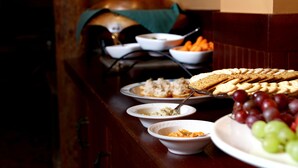 A buffet table with various dishes including bread, fruits, and dips.
