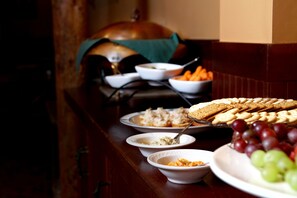 A buffet table with various dishes including bread, fruits, and dips.