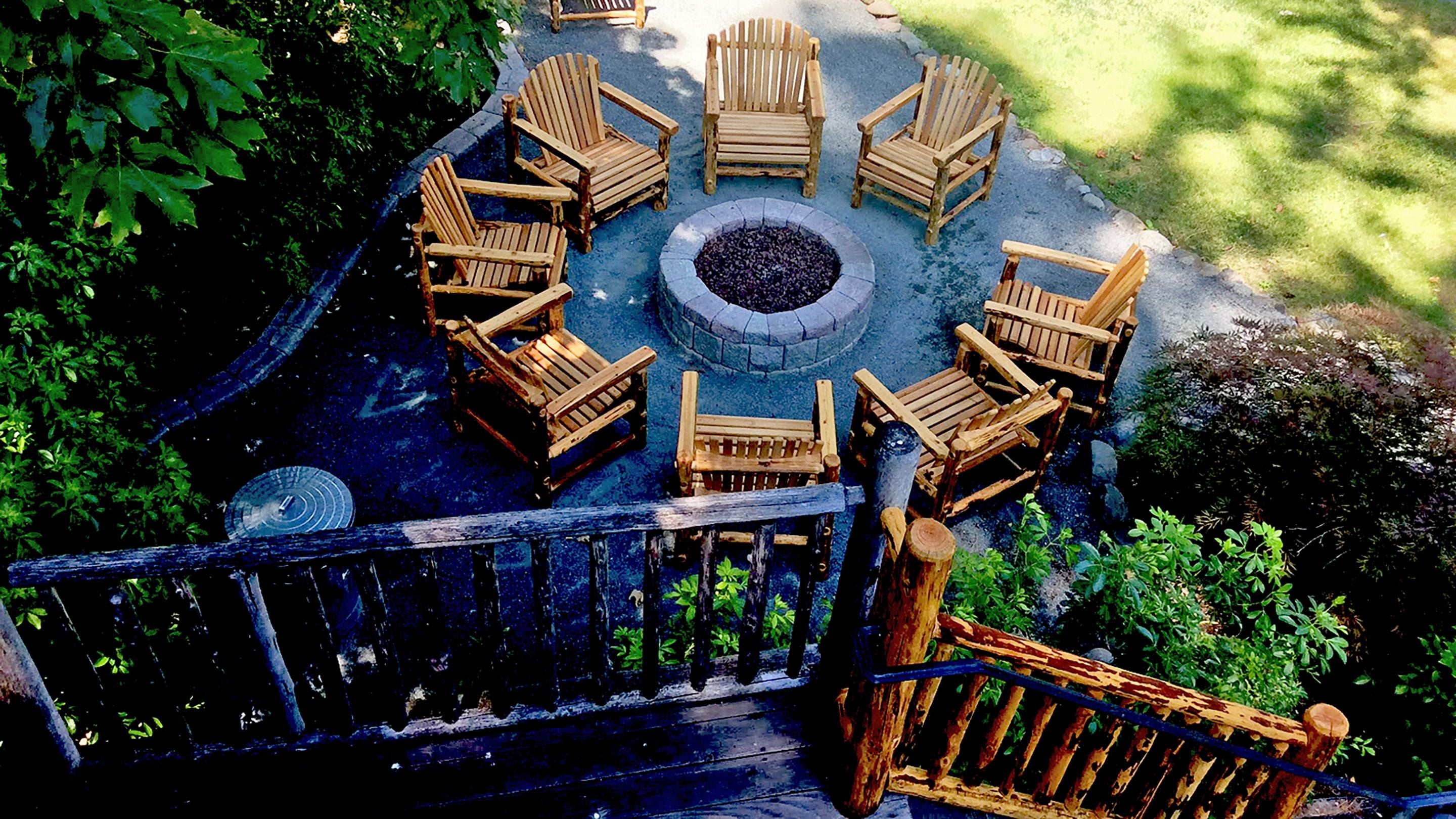 A circular outdoor seating area with wooden chairs and a central fire pit.
