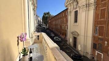 A balcony with a table, chairs, a potted orchid, and a bottle of wine.