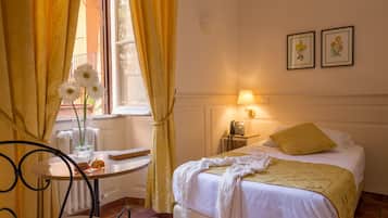 A hotel room with a bed, a bedside table, a lamp, and a window with curtains.