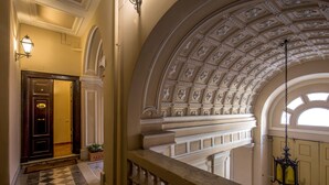 A grand hallway with a checkered floor, a wooden door, and a balcony with a decorative ceiling. - Aenea Superior Inn (Rome)
