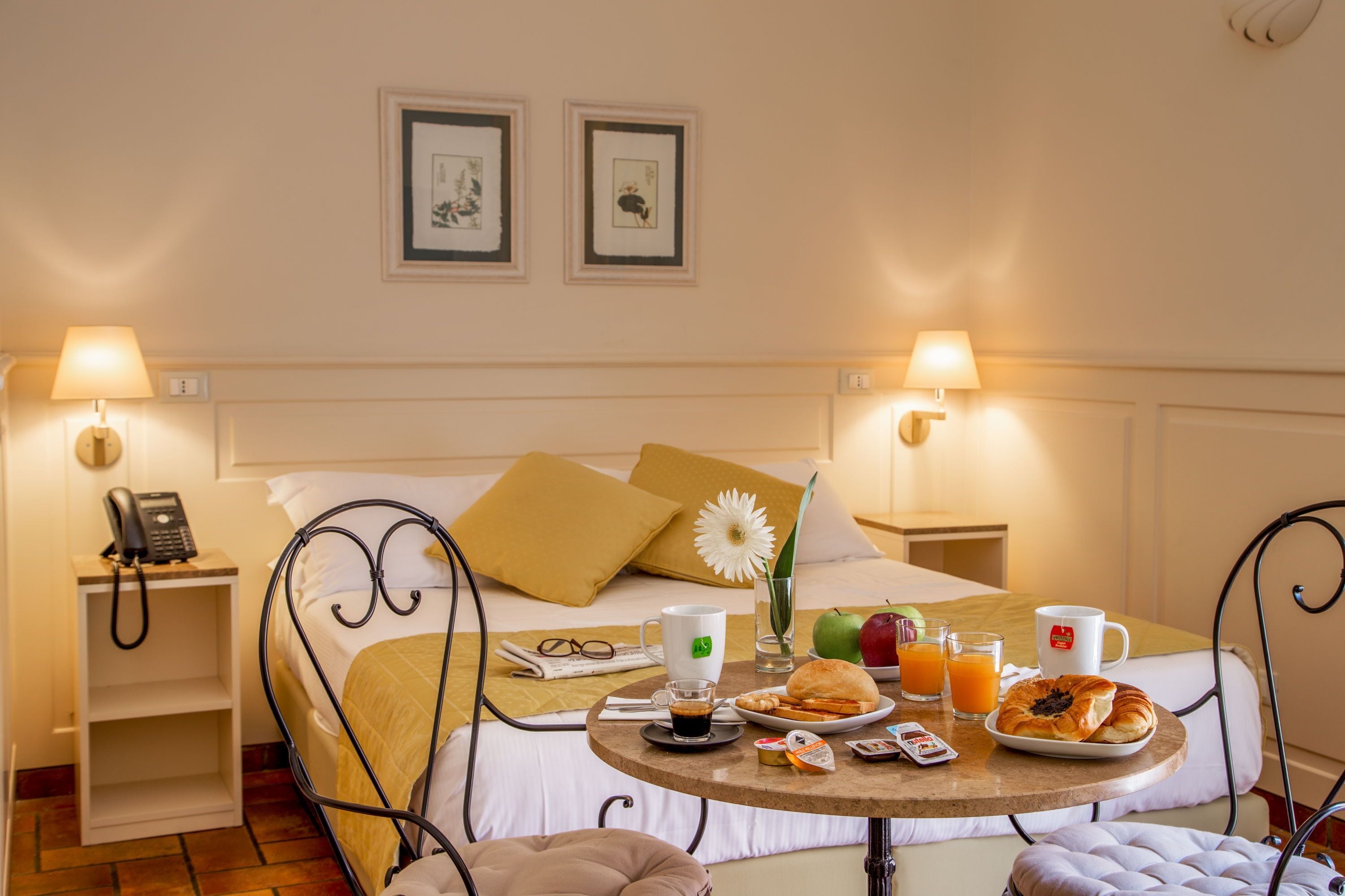 A neatly arranged hotel room with a bed, bedside tables, a round breakfast table, and a small armchair.