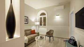 Una sala de estar moderna con un sofá, una pequeña mesa redonda, una silla, un jarrón grande y un banco con un bolso de mano.