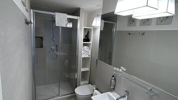 Ein modernes Badezimmer mit einer Glasdusche, einem weißen Waschbecken und einer Toilette.